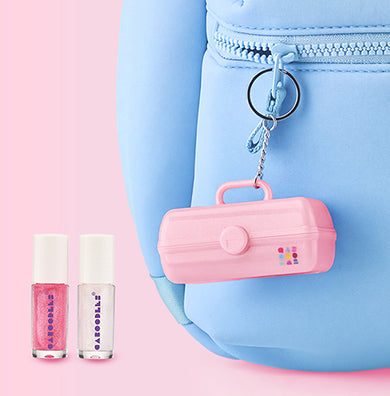 Blue bag with branded Caboodles small keychain hanging. Next to it are two lip glosses, one pink and one while with Caboodles brand logo against a pink background. 